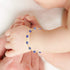 A close-up of a baby's hand adorned with the Blue Evil Eye Charm Bracelet for Protection Good Luck Turkish Nazar, delicately holding an adult's finger.